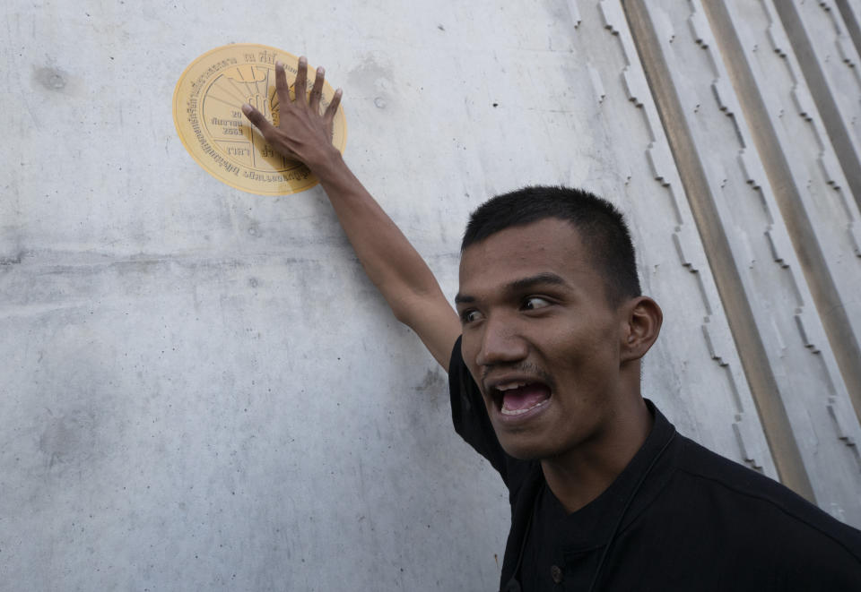 Pro-democracy demonstrator Panupong Jadnok puts a sticker of a plaque marking Thailand's transition to democracy on the wall of Parliament during a protest in Bangkok, Thailand, Thursday, Sept. 24, 2020. Lawmakers in Thailand are expected to vote Thursday on six proposed amendments to the constitution, as protesters supporting pro-democratic charter reforms gathered outside the parliament building. (AP Photo/Sakchai Lalit)