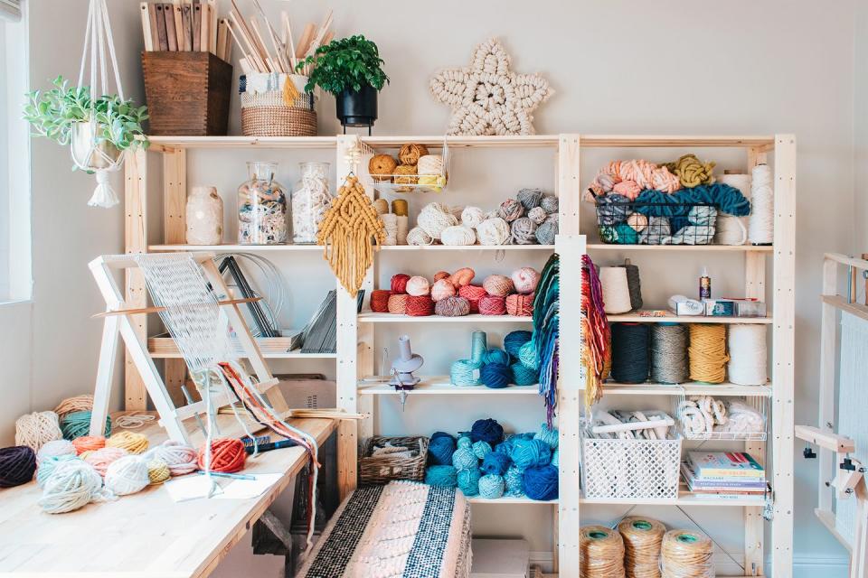 <p>If your craft room is dedicated to weaving and/or knitting materials, take note of this workshop belonging to artist Lindsey Campbell, who runs the weaving-centric blog <a href="https://www.hellohydrangea.com/" rel="nofollow noopener" target="_blank" data-ylk="slk:Hello Hydrangea;elm:context_link;itc:0;sec:content-canvas" class="link ">Hello Hydrangea</a>. Keep all your things easily accessible with a modular wall shelving unit so all crafting materials (yarn, rope, winders, and more) stays organized. Then use glass jars to host remnants for recycling and baskets to assist with organization. </p>