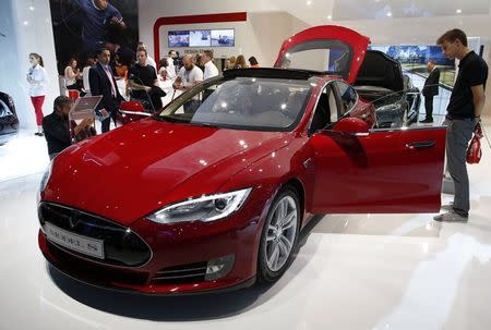 Visitors look at a Tesla Model S car displayed on media day at the Paris Mondial de l'Automobile, October 2, 2014. REUTERS/Benoit Tessier