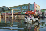 Shopkeepers at the Yubei Agricultural and Aquatic Products World leave the market on a motor tricycle in Xinxiang in central China's Henan Province, Monday, July 26, 2021. Record rain in Xinxiang last week left the produce and seafood market soaked in water. Dozens of people died in the floods that immersed large swaths of central China's Henan province in water. (AP Photo/Dake Kang)