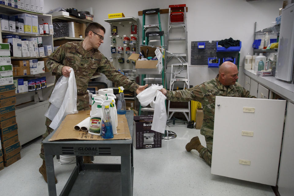 U.S. Army Field Band members mandolin player Staff Sgt. Joseph Bennett, originally from Roanoke, Va., left, and vocalist Sgt. 1st Class, Randall Wight, originally fo Syracuse, N.Y., prepare to clean and sanitize the rehearsal area of their daily "We Stand Ready" virtual concert series at Fort George G. Meade in Fort Meade, Md., Wednesday, March 25, 2020. The Army Field Band's mission is to bring the military's story to the American people. And they're not letting the coronavirus get in the way. (AP Photo/Carolyn Kaster)