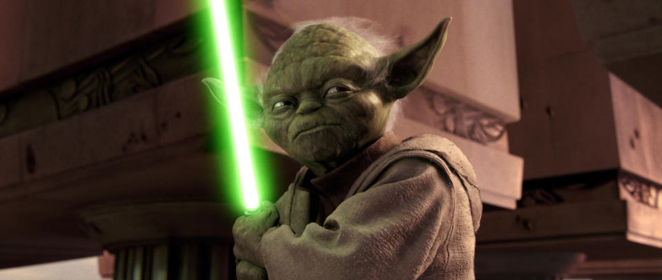 Yoda holding a lightsaber.