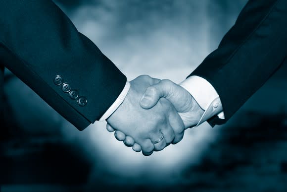 Two businessmen in suits shaking hands, as if in agreement.