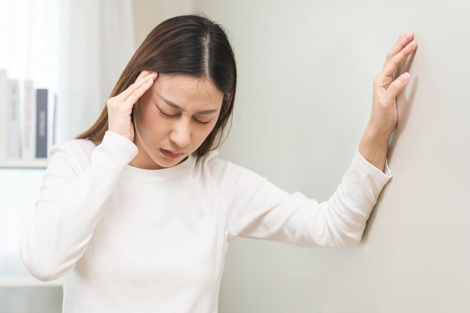 Una mujer se agarra la oreja con dolor.