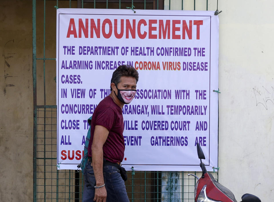 A man wearing a protective mask walks past a sign at a basketball court that announces it's temporary closure as a precautionary measure against the spread of the new coronavirus in suburban Quezon city, Manila, Philipines on Saturday March 14, 2020. Philippine officials on Saturday declared a night curfew in the capital and said millions of people in the densely populated region could only go out of their homes for work, buy necessities and medical emergencies at daytime under a monthlong quarantine to be imposed to fight the new coronavirus. (AP Photo/Aaron Favila)