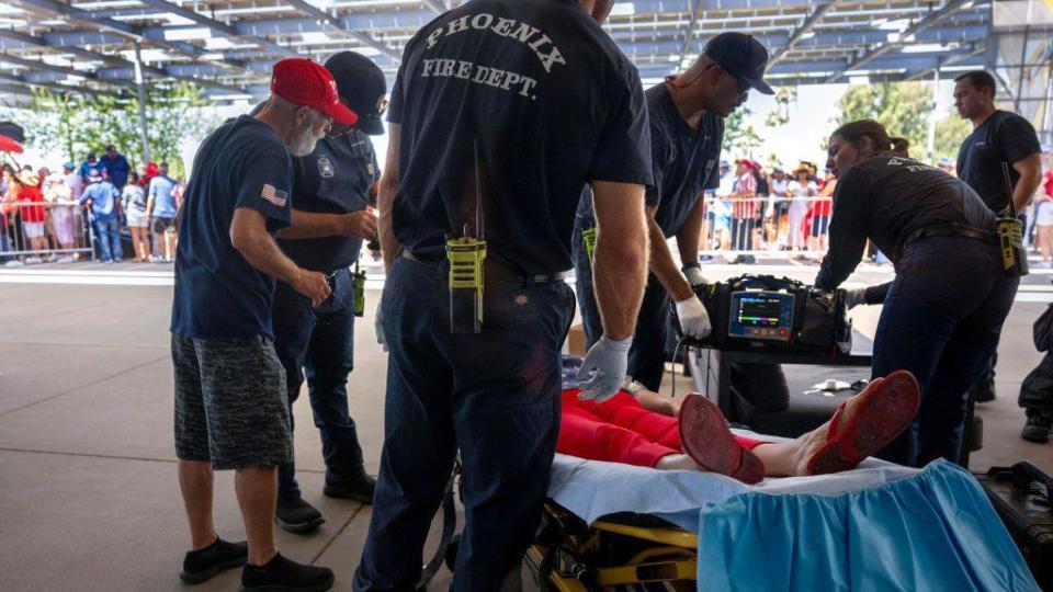 As temperatures reach 108 degrees Farenheit (42C), a woman is tended to for heat exhaustion as supporters line up before former US President and 2024 Republican presidential candidate Donald Trump participates in a town hall event at Dream City Church in Phoenix, Arizona, on June 6, 2024