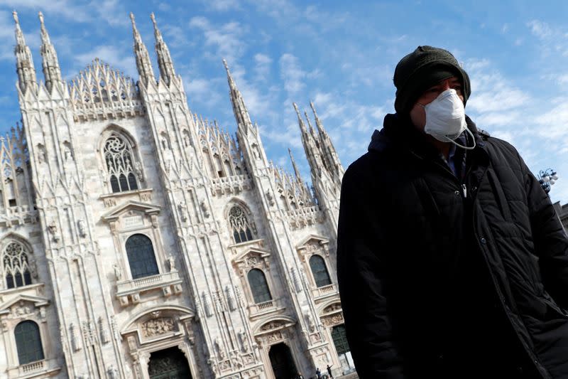 A man wearing a protective face mask to prevent contracting the coronavirus walks past the Duomo Cathedral in Milan