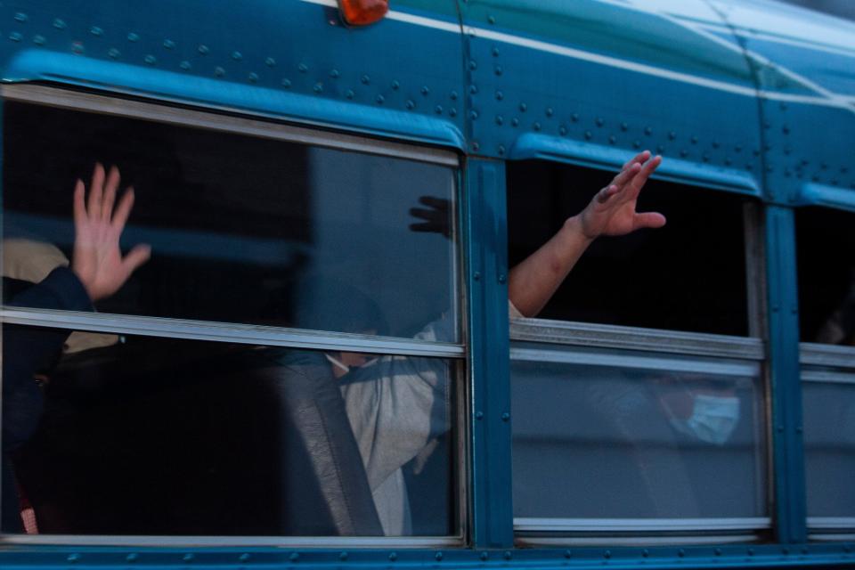 In this May 4, 2020, file photo, Guatemalans deported from the United States, wave from a bus after arriving at La Aurora airport in Guatemala City.