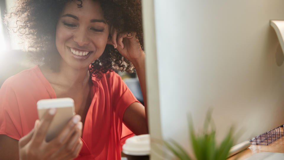 Shot of an attractive young woman using her mobile phone while sitting at her office desk.