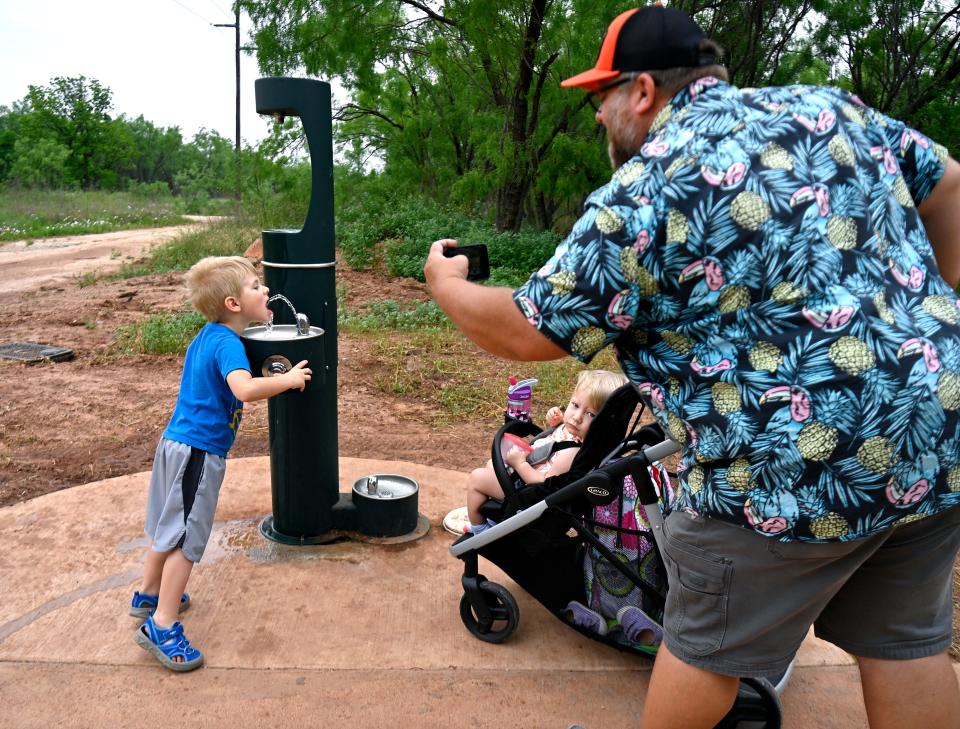 Andrew Wheeler photographs his 5-year-old son Anderson as they stop at a water station along the newly-opened Cedar Creek Waterway trail April 27.