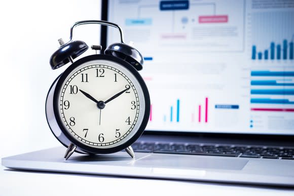 Alarm clock sitting on top of computer.