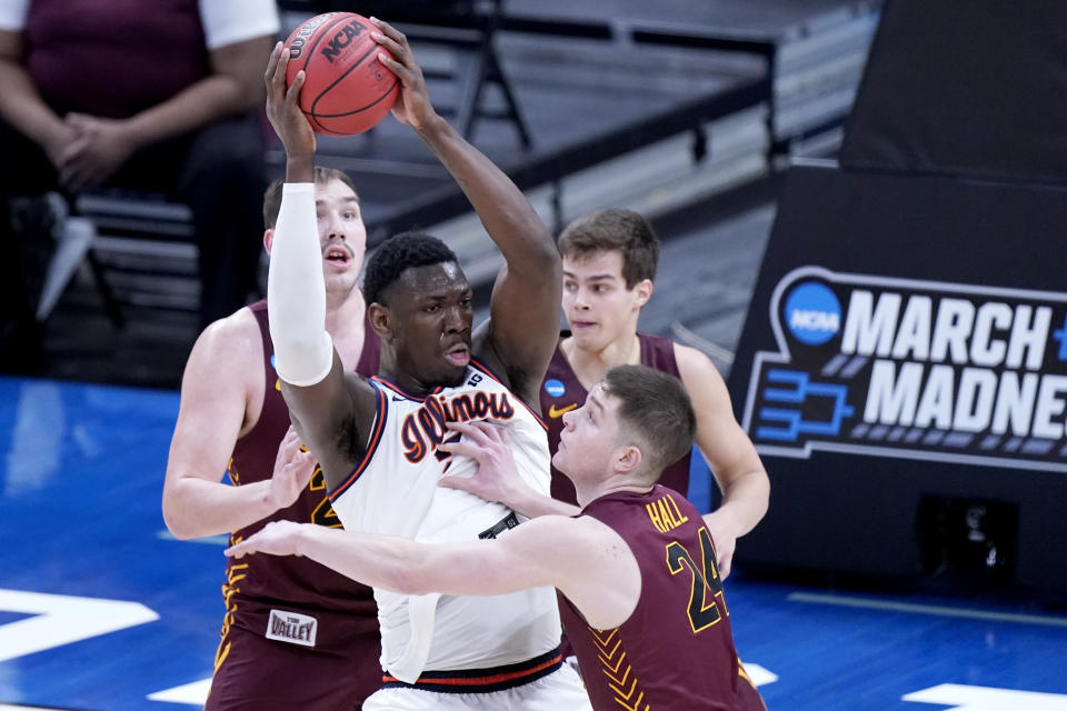 Illinois' Kofi Cockburn, center, is defended by Loyola of Chicago's Tate Hall (24) during the first half of a college basketball game in the second round of the NCAA tournament at Bankers Life Fieldhouse in Indianapolis Sunday, March 21, 2021. (AP Photo/Mark Humphrey)