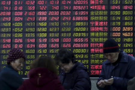 Investors stand in front of an electronic board showing stock information on the first trading day after the week-long Lunar New Year holiday at a brokerage house in Shanghai