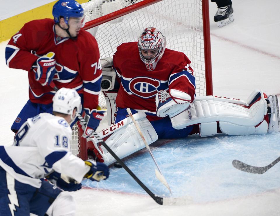 Montreal Canadiens goalie Carey Price (31) makes a save on Tampa Bay Lightning left wing Ondrej Palat (18) as Montreal Canadiens defenseman Alexei Emelin (74) looks on during second period National Hockey League Stanley Cup playoff action on Tuesday, April 22, 2014 in Montreal. (AP Photo/The Canadian Press, Ryan Remiorz)