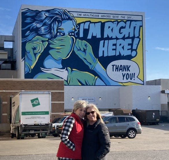 Lee Ann Ernst, a nurse at St. Elizabeth and coordinator of the infectious disease response team; and Teresa Cecil, director of environmental services, stand in front of a new mural in Newport honoring health care workers.