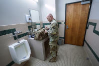 Capt. Michael Switzer readies for bed to go to sleep in his office at Camp Beauregard in Pineville, La., Friday, July 30, 2021. (AP Photo/Gerald Herbert)