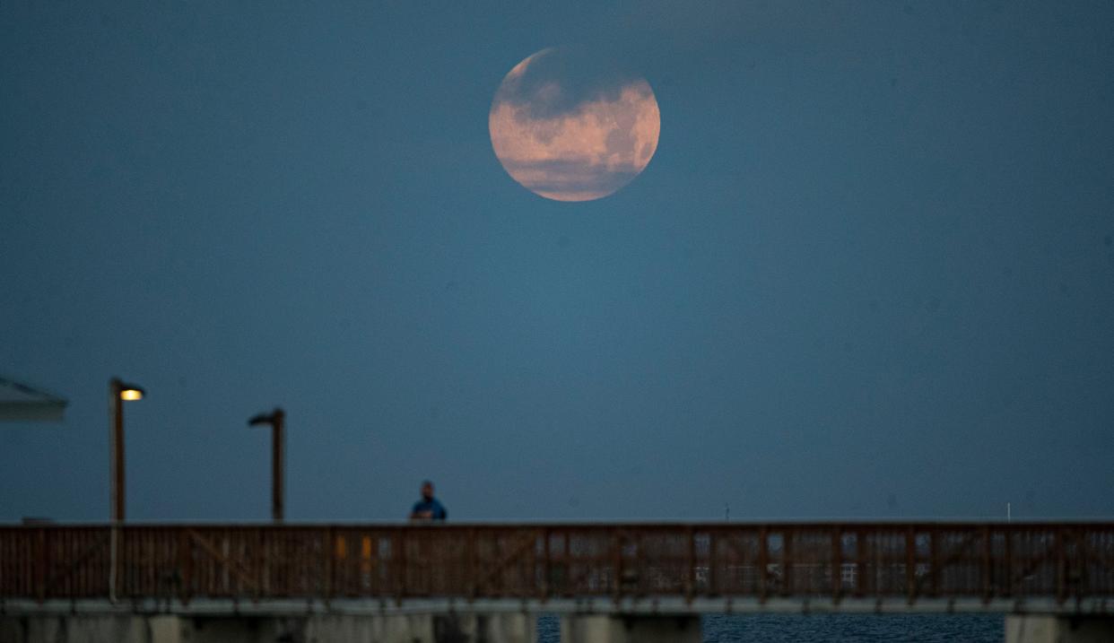 The so-called "pink moon" can be seen April 16, 2022 setting over the Fort Myers Beach pier.