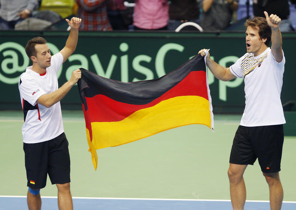 Germany's double Philipp Kohlschreiber, left, and Tommy Haas celebrate with the German flag after beating Spain's Fernando Verdasco and David Marrero during a Davis Cup World Group first round tennis match between Germany and Spain in Frankfurt, Germany, Saturday, Feb. 1, 2014. After winning the double, Germany has now a 3-0 lead and advances to the next round. (AP Photo/Michael Probst)
