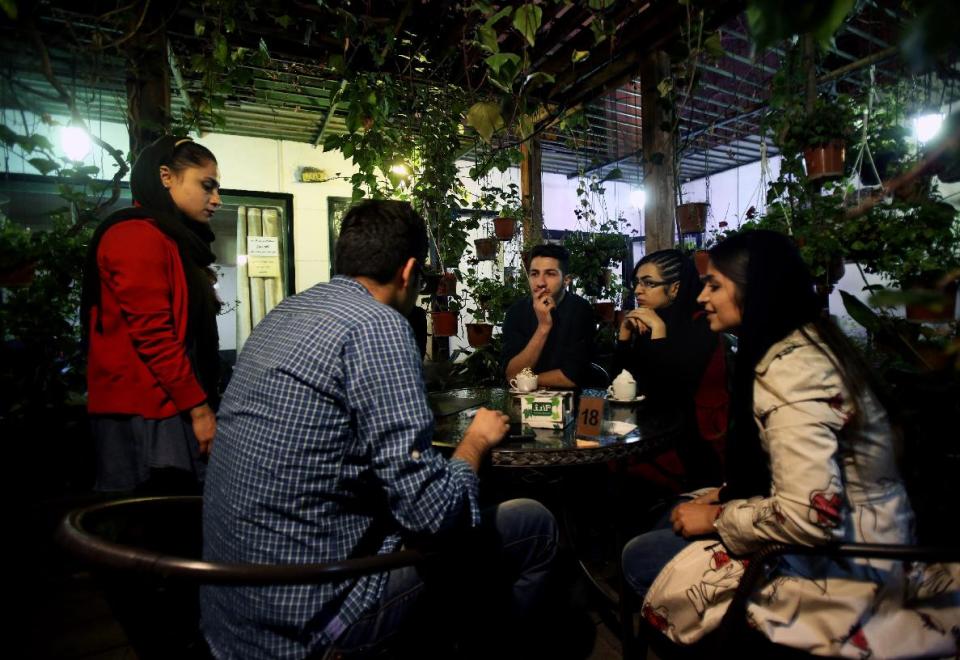 In this Tuesday, March 4, 2014 photo, young Iranian adults sit at a cafe in Tehran, Iran. For years Iranian authorities kept the number of cafes limited since they were seen as a symbol of Western influence and places to spread non-Islamic beliefs. But reports of cafes being shut because they violate “Islamic dignities” have dropped markedly in recent months, suggesting a growing tolerance by the authorities. (AP Photo/Vahid Salemi)