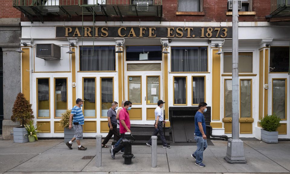 People walk by the Paris Cafe, Tuesday, Aug. 4, 2020 in New York's South Street Seaport. Many iconic bars, dinners and restaurants have closed or are teetering towards closing due to the coronavirus pandemic. (AP Photo/Mark Lennihan)