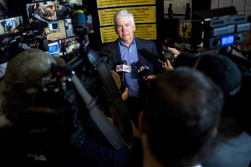 FILE - In this Monday, June 6, 2016 file photo, journalists surround around Gov. Rick Snyder to ask him questions about the Flint water crisis after he toured skilled trades programs at Mott Community College in Flint, Mich. Flint had one of the worst man-made environmental debacles in U.S. history. Lead infected the distribution system in the city of 100,000, which was under the thumb of financial managers appointed by Snyder. Officials finally took action after a doctor reported high levels of lead in children. (Jake May/The Flint Journal - MLive.com via AP)