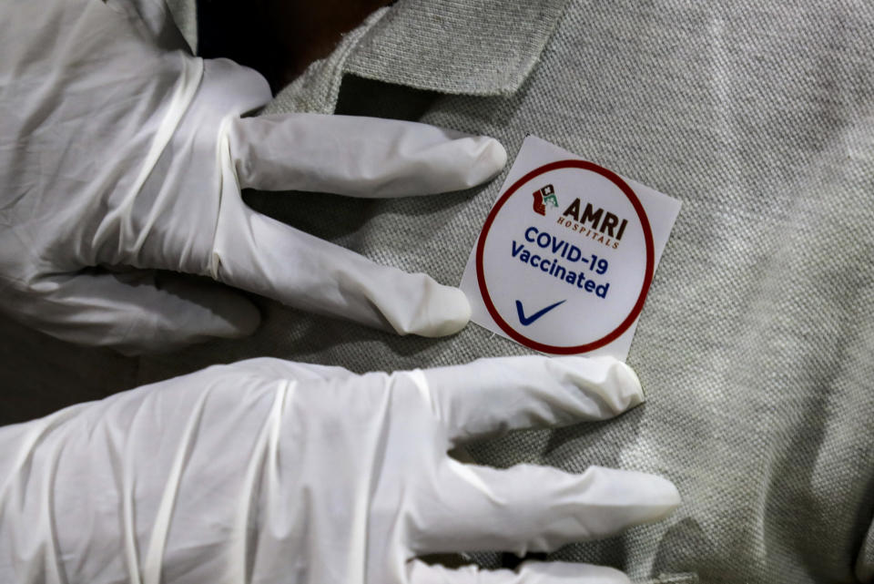 A hospital staff puts a badge on the chest of a colleague after being administered COVID-19 vaccine at a hospital in Kolkata, India, Saturday, Jan. 16, 2021. India started inoculating health workers Saturday in what is likely the world's largest COVID-19 vaccination campaign, joining the ranks of wealthier nations where the effort is already well underway. (AP Photo/Bikas Das)