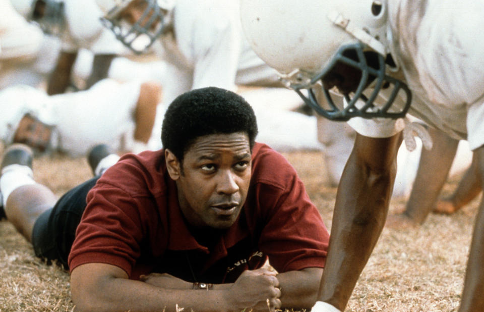 Denzel Washington lying on the grass talking to a football player