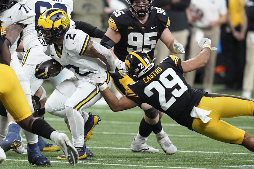 Michigan running back Blake Corum (2) runs from Iowa defensive back Sebastian Castro (29) during the second half of the Big Ten championship NCAA college football game, Saturday, Dec. 2, 2023, in Indianapolis. (AP Photo/Darron Cummings)