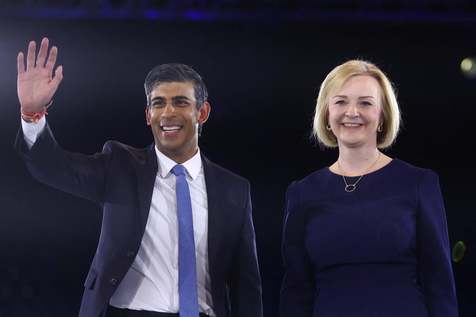 Rishi Sunak waves, with Liz Truss standing by his side.