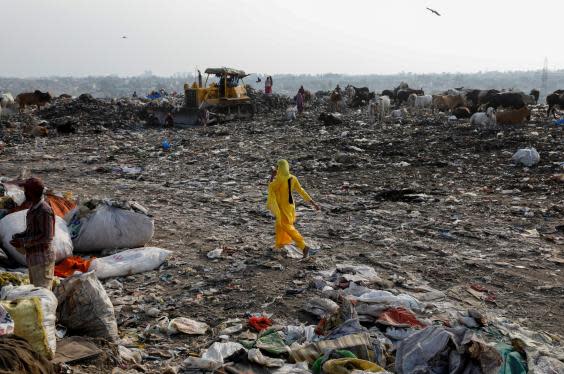 A woman walks through the New Delhi waste site (Reuters)