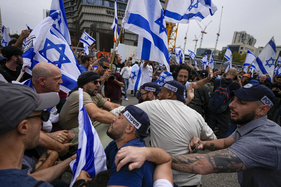 Israelis protest against plans by Prime Minister Benjamin Netanyahu's government to overhaul the judicial system scuffle with police in Tel Aviv, Israel, Thursday, March 23, 2023. (AP Photo/Ohad Zwigenberg)