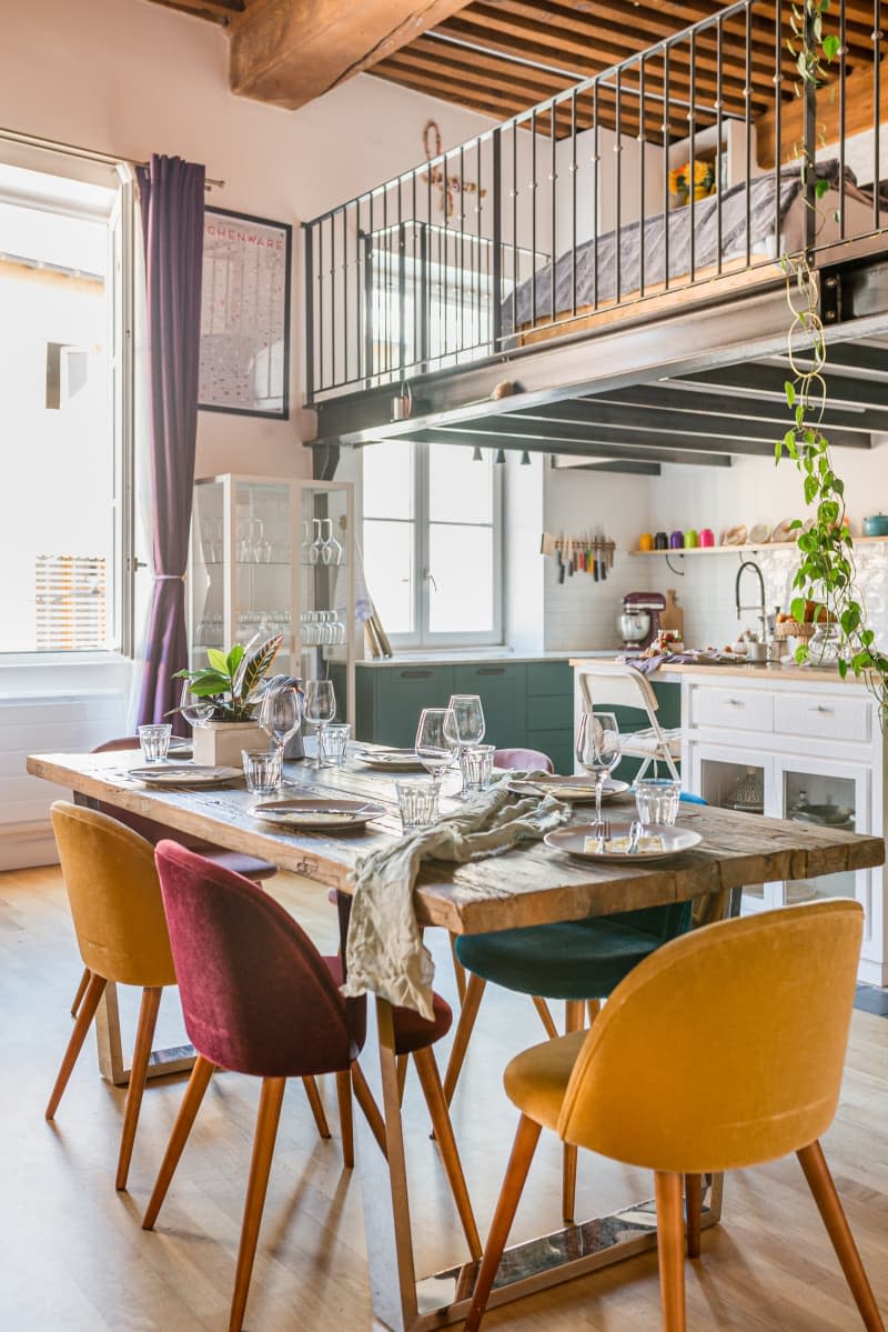 A wooden dining table with colorful seats.