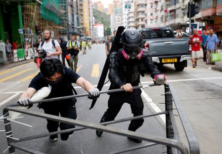 Ah Lung and another protester push a barricade to the frontline during a protest in Sham Shui Po neighbourhood of Hong Kong