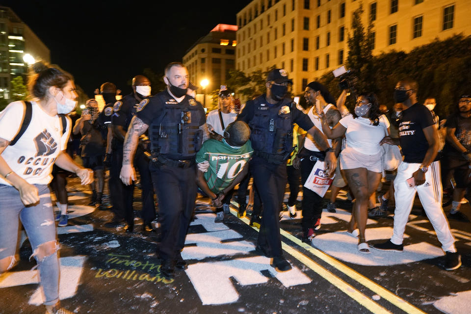 Metropolitan Police carry away a handcuffed protestor along a section of 16th Street, Northwest, renamed Black Lives Matter Plaza, Thursday night , Aug. 27, 2020, in Washington, after President Donald Trump had finished delivering his acceptance speech from the White House South Lawn. (AP Photo/Julio Cortez)