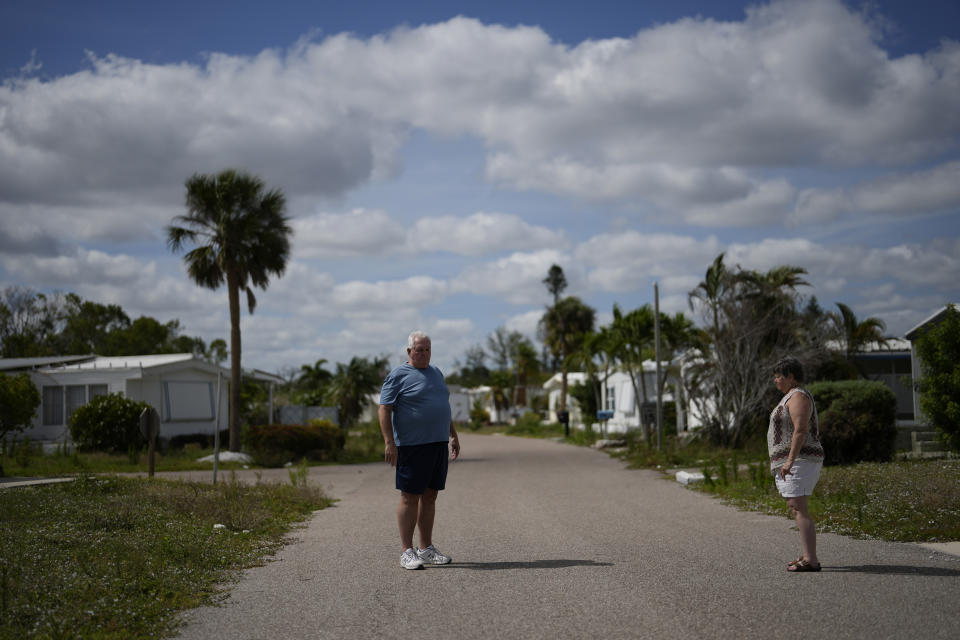 Robert Burton and his partner Cindy Lewis, both 71, stand outside their home in the now deserted Century 21 mobile home community in Fort Myers, Fla., Tuesday, May 2, 2023. After Hurricane Ian flooded their home, Burton and Lewis spent months couch surfing with friends and family around the country until finally a small apartment was provided through the Federal Emergency Management Agency. They can stay there until March 2024 while they look for a new place to live. (AP Photo/Rebecca Blackwell)