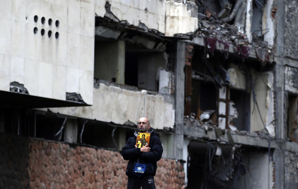 <p>A man holds an icon and stands in front of the destroyed former Yugoslav army headquarters, during a protest in Belgrade, Serbia, April 8, 2017. Thousands of people are blowing whistles and banging pots outside the Serbian government headquarters to protest the election of powerful Prime Minister Aleksandar Vucic as the country’s new president. (Photo: Darko Vojinovic/AP) </p>