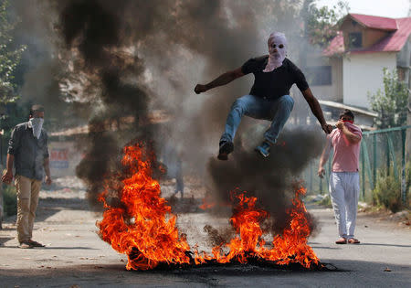 A man in a balaclava jumps over burning debris during a protest against the recent killings in Kashmir, in Srinagar, India September 12, 2016. REUTERS/Danish Ismail/File Photo