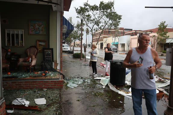 People walk past damaged stores after hurricane Michael passed through downtown Panama City, Florida.