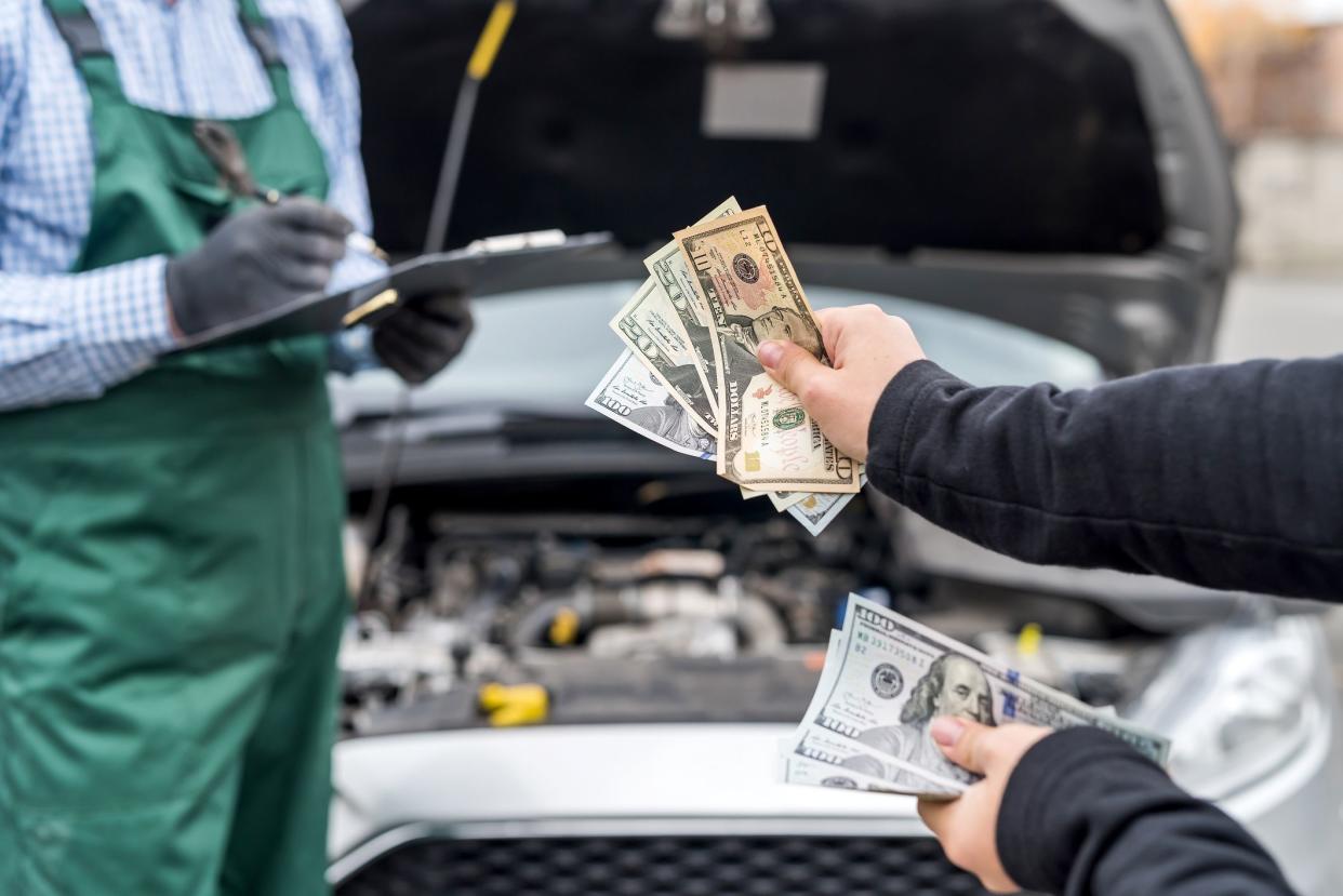 Female hands giving dollar banknotes to mechanic