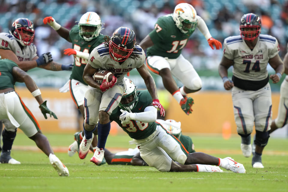 Jackson State running back Irv Mulligan (5) runs to avoid a tackle by Florida A&M defensive back Andre Powell Jr. (36) during the second half of the Orange Blossom Classic NCAA college football game, Sunday, Sept. 3, 2023, in Miami Gardens, Fla. (AP Photo/Lynne Sladky)