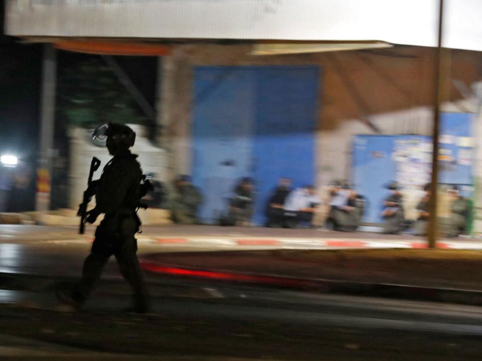 Israeli forces take cover as a siren rings out to signal an incoming rocket attack  in the mixed Jewish-Arab city of Lod during clashes between Israeli far-right extremists and Arab-Israelis (AHMAD GHARABLI/AFP via Getty Images)