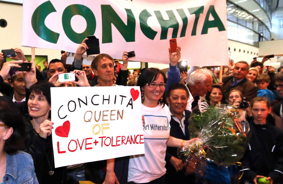 Supporters of Austrian singer Conchita Wurst celebrate during the singer's arrival at Vienna's Schwechat airport, Austria, Sunday, May 11, 2014. Bearded drag queen Conchita Wurst has made a triumphant return to Austria after winning the Eurovision Song Contest in Copenhagen Saturday in what the country's president called a victory for tolerance in Europe. (AP Photo/Ronald Zak)