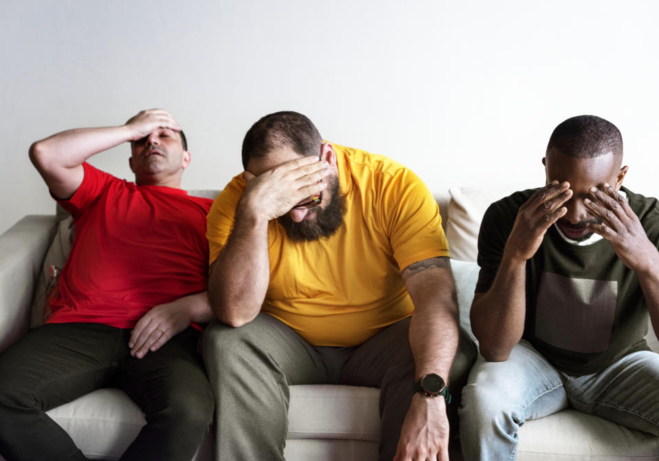 Three distressed guys on a sofa.