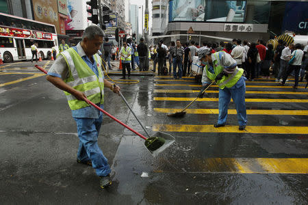 Workers sweep the main Nathan Road at Mongkok shopping district, after police cleared a protest site which has occupied the street for weeks, in Hong Kong, November 26, 2014. REUTERS/Liau Chung-ren