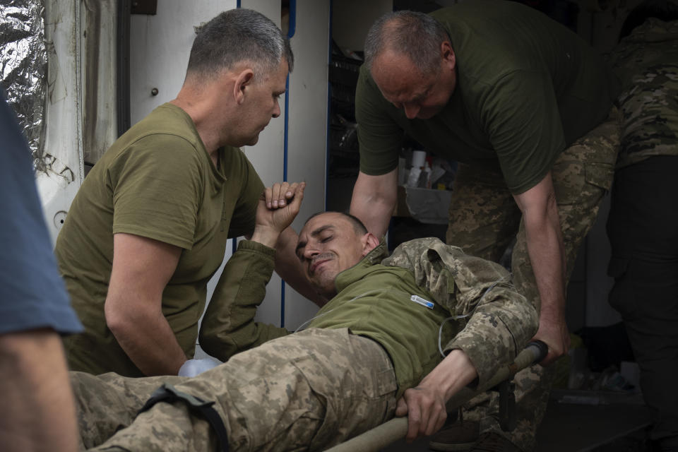 Ukrainian soldiers carry their wounded fellow at a medical stabilisation point near Bakhmut, Donetsk region, Ukraine, Wednesday, May 24, 2023. (AP Photo/Efrem Lukatsky)