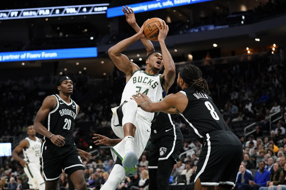 Milwaukee Bucks' Giannis Antetokounmpo, middle, drives to the basket against Brooklyn Nets' Patty Mills (8) during the second half of an NBA preseason basketball game Wednesday, Oct. 12, 2022, in Milwaukee. (AP Photo/Aaron Gash)