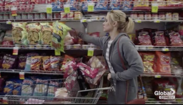 a woman shoving snacks into her shopping cart