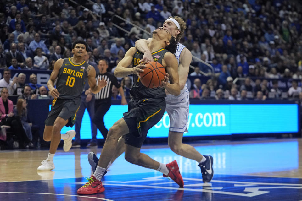 BYU guard Richie Saunders, rear, fouls Baylor guard Miro Little (1) during the first half of an NCAA college basketball game Tuesday, Feb. 20, 2024, in Provo, Utah. (AP Photo/Rick Bowmer)