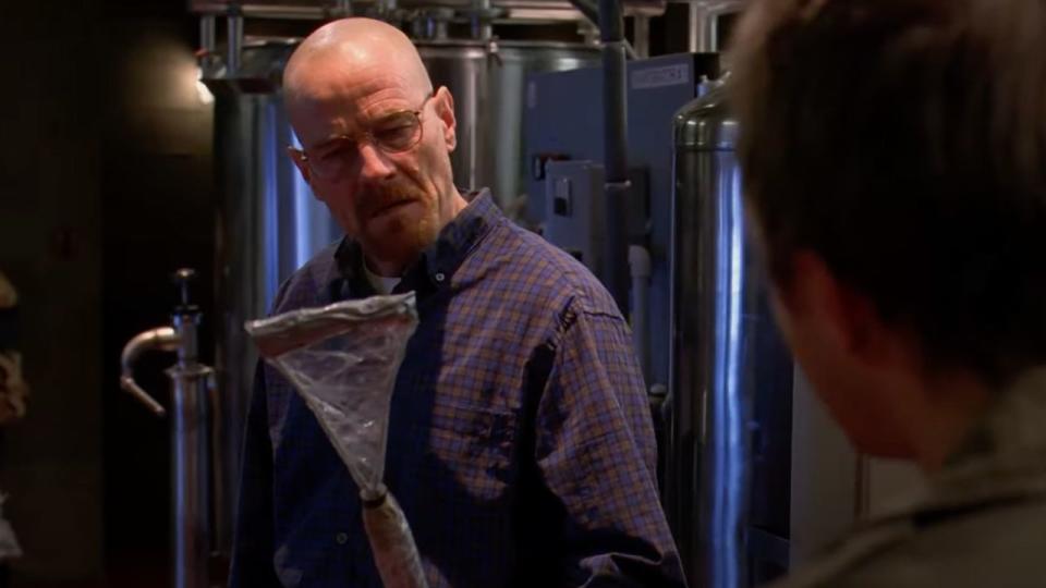 Walter White holding a homemade fly swatter in the lab.
