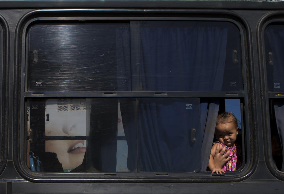 In this Aug. 18, 2018 photo, a baby peers out the window of a bus leaving from Intipuca, El Salvador to nearby San Miguel. Almost a third of Salvadorans currently live in the U.S., more than 2 million from a country of 6.3 million, a diaspora fueled by civil war, natural disasters and grinding poverty. (AP Photo/Rebecca Blackwell)